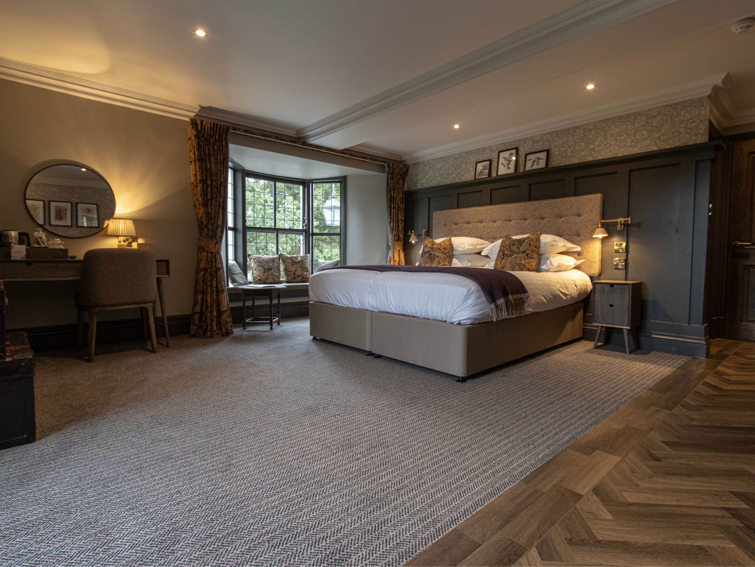 Spacious bedroom featuring a king-size bed and a large bay window letting in natural light.