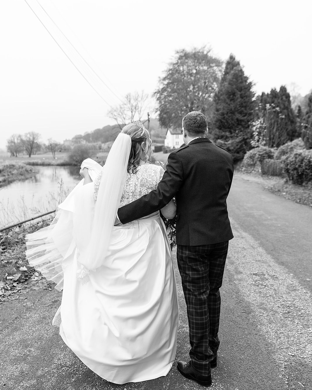 Just married couple walking down a countryside lane arm in arm.